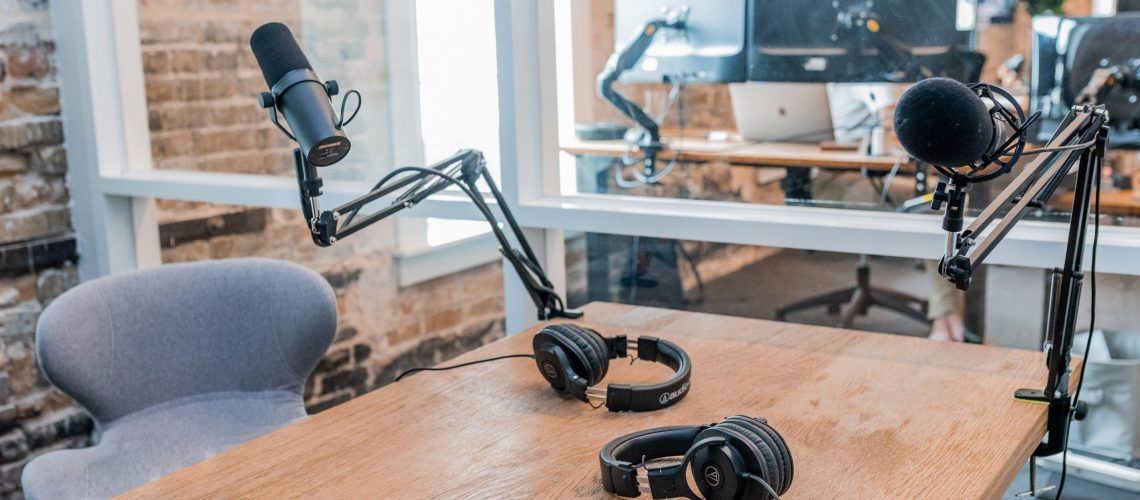 Photo by Austin Distel two black headphones on brown wooden table